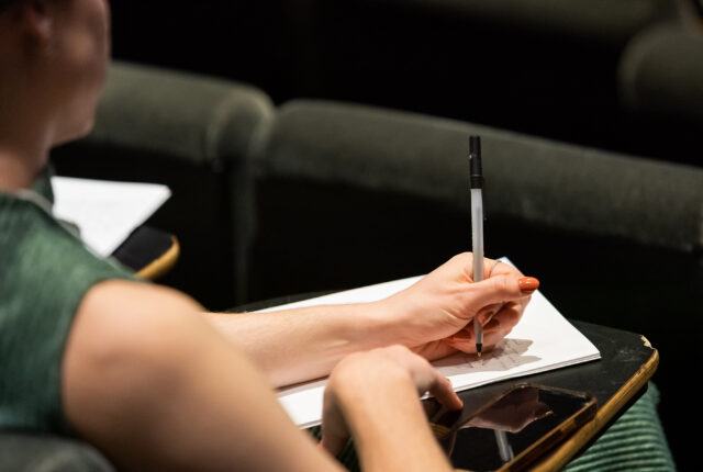 A person taking notes with a pen and notebook