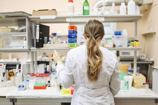 Woman In White Long Sleeved Laboratory Gown Conducting Experiments